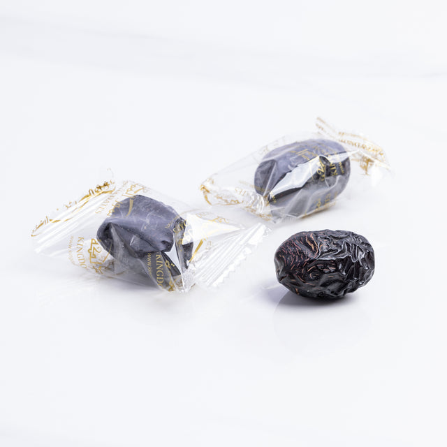 Ajwa Al Madina dates wrapped in a decorative paper, showcasing their dark, glossy appearance and premium quality from Kingdom Dates UAE.