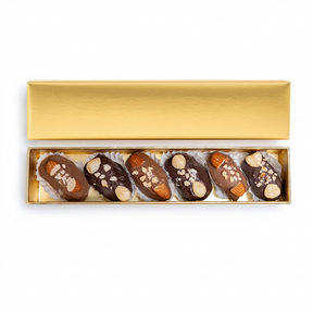 Golden mixed covered chocolate dates with nuts in a gift box, showcasing glossy chocolates and nut-filled dates from kingdomdatesuae.