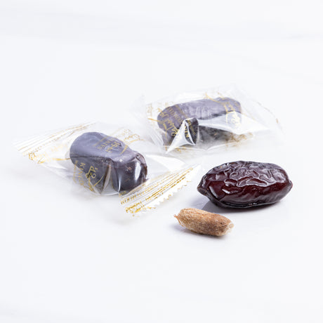 Wrapped Safawi Al Madina dates from Kingdom Dates UAE, showcasing glossy, dark dates in a traditional presentation.