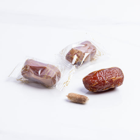 Wrapped Sagi Dates from Kingdom Dates UAE displayed in a natural setting, showcasing fresh, glossy, and plump dates.
